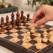 Jeu d’échecs Le Nomade ébène — une main déplace une pièce