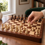 Jeu d’échecs Le Nomade marqueté — une main déplace une pièce