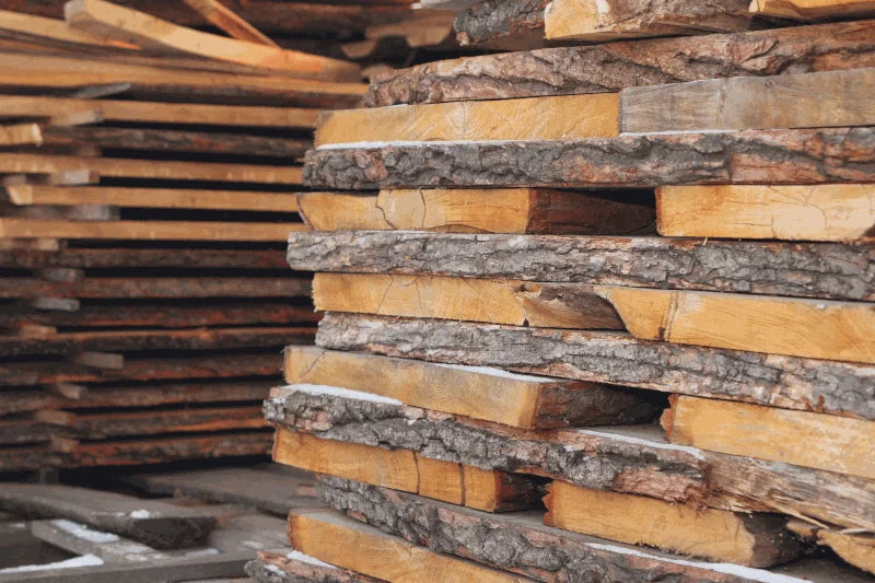 Planches de bois brut avec leur écorce, empilées pour sécher