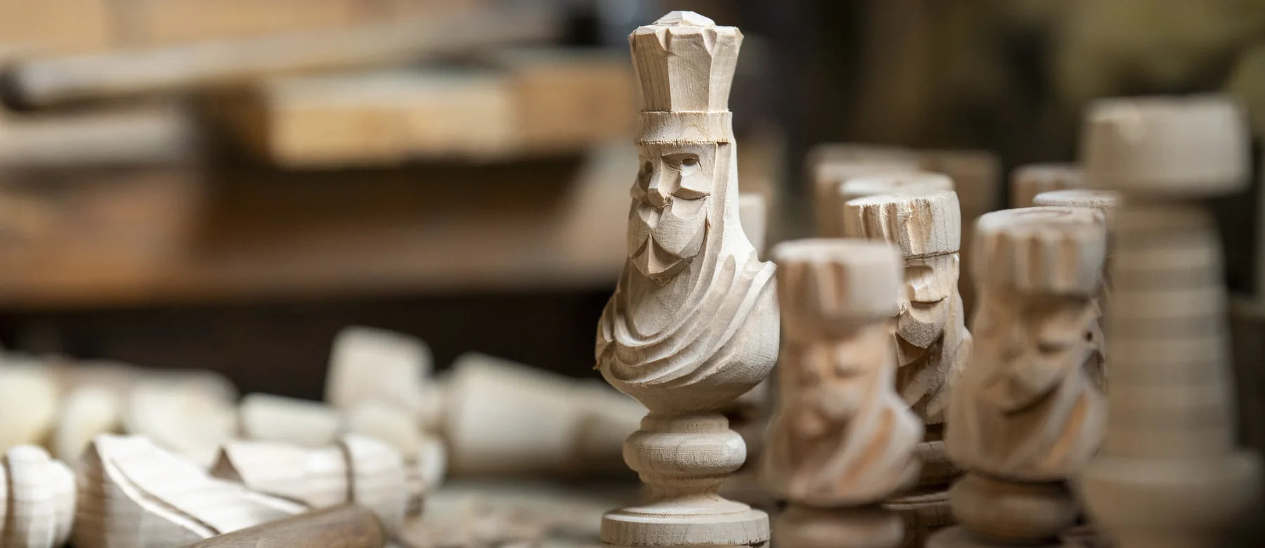 Rois et cavaliers sculptés dans le bois brut, posés sur l’établi au milieu des copeaux