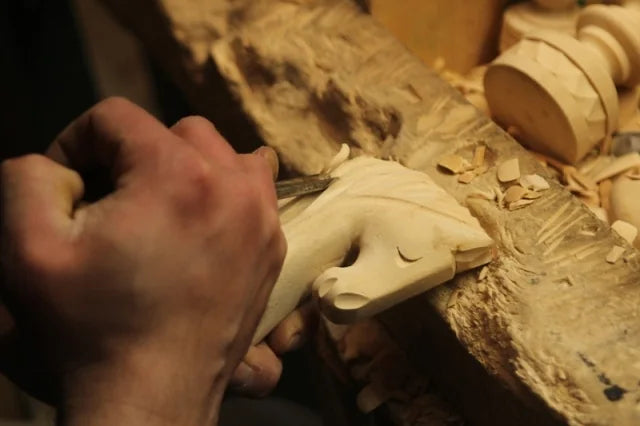 Mains d’artisan qui taillent la tête d’un cavalier dans le bois