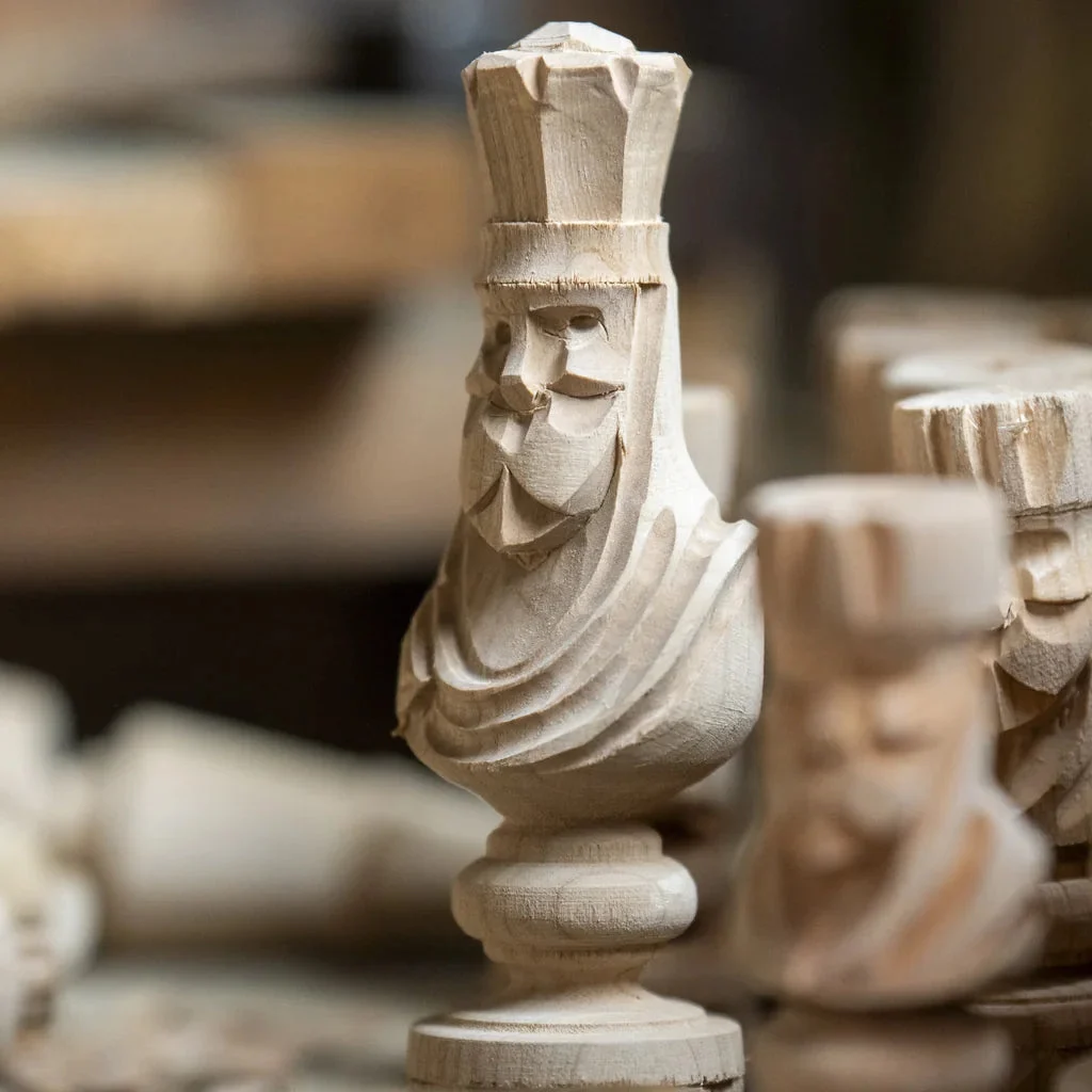 Hand-carved chess pieces in raw wood on the workshop bench